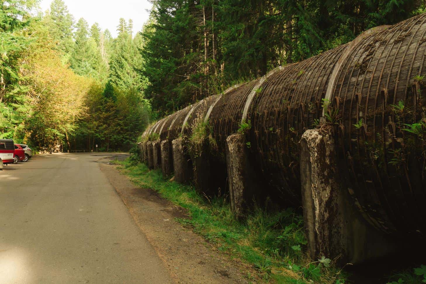 Wooden North Umpqua hydroelectric pipeline beside the Toketee Falls trailhead parking area, with parked cars on the left