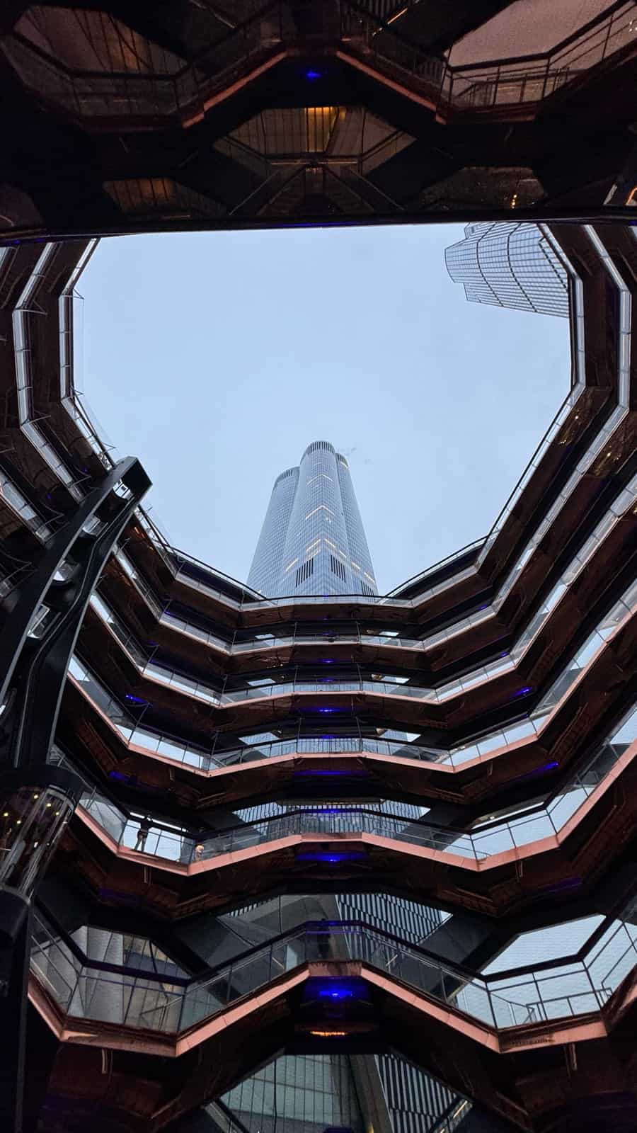 Looking up from inside the Vessel toward a Hudson Yards skyscraper