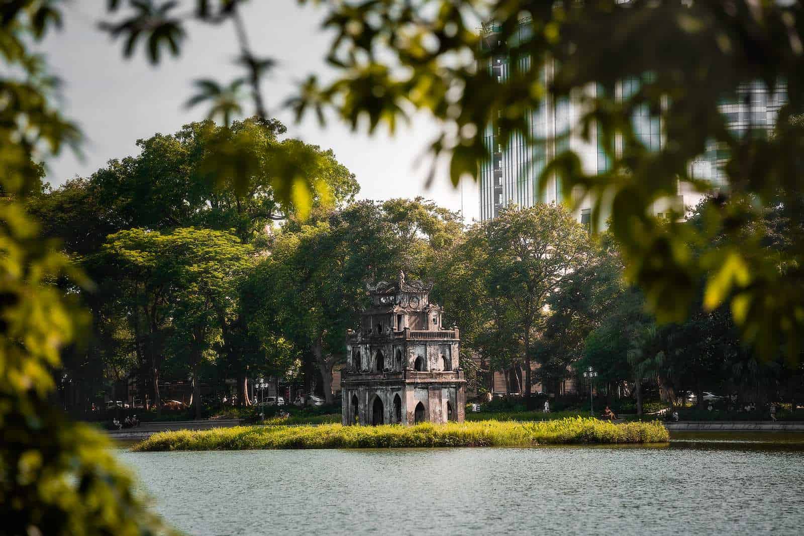 Turtle Tower on Hoan Kiem Lake framed by trees in Hanoi, Vietnam
