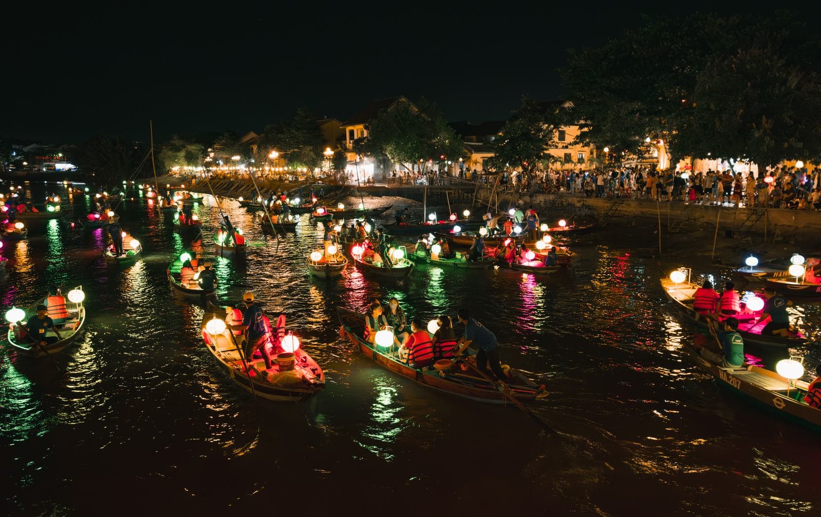 Colorful lanterns glowing on boats along the river in Hoi An's Ancient Town at night