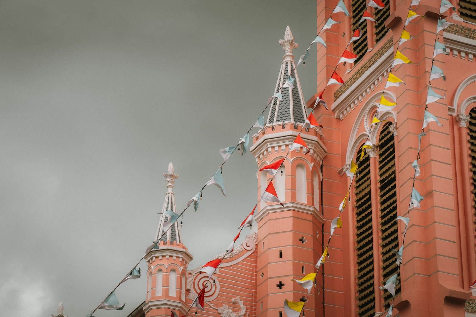 White-trimmed spires and arched windows on the pink facade of Tan Dinh Church