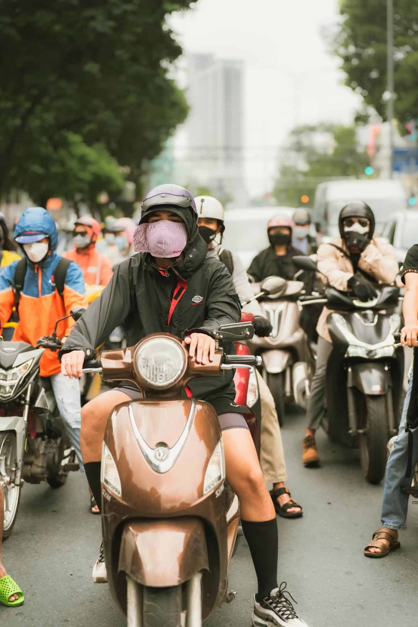 Helmeted motorbike riders waiting in traffic on a street in Ho Chi Minh City