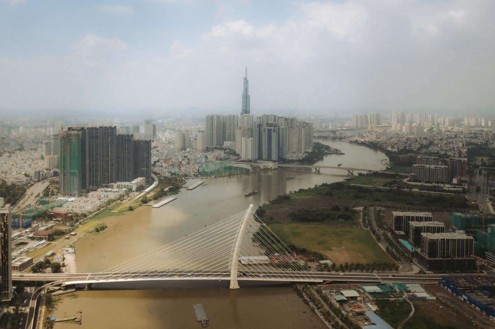 Aerial view of a cable-stayed bridge across the Saigon River with Landmark 81 in the distance