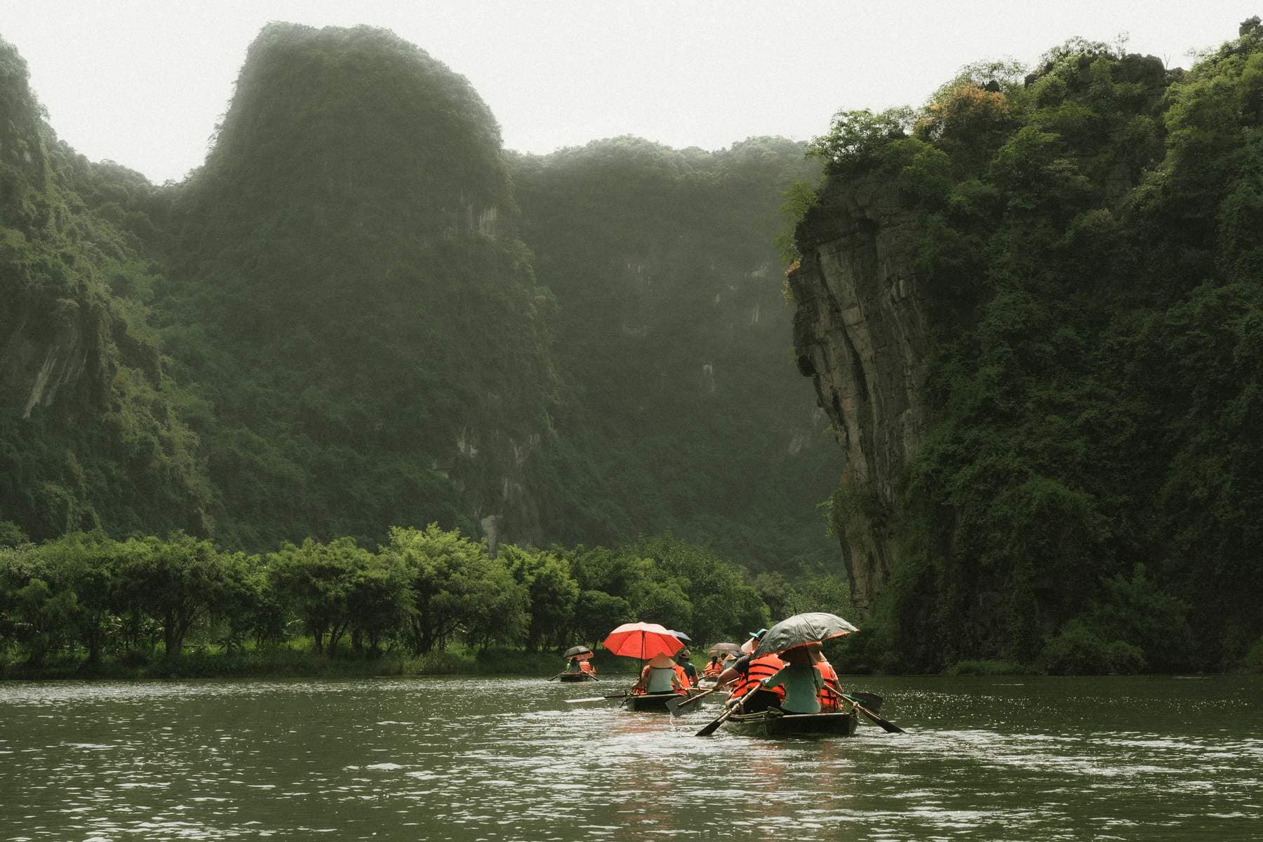 Rowboats passing beneath limestone cliffs on the Trang An boat route