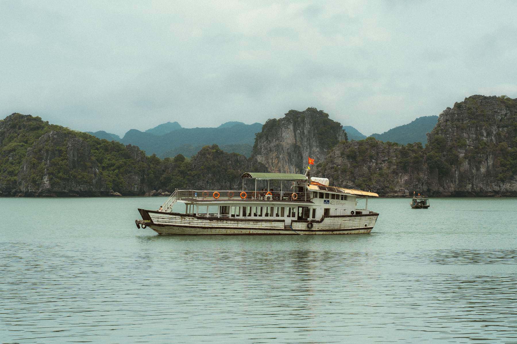 Day cruise boat passing limestone islands in Ha Long Bay
