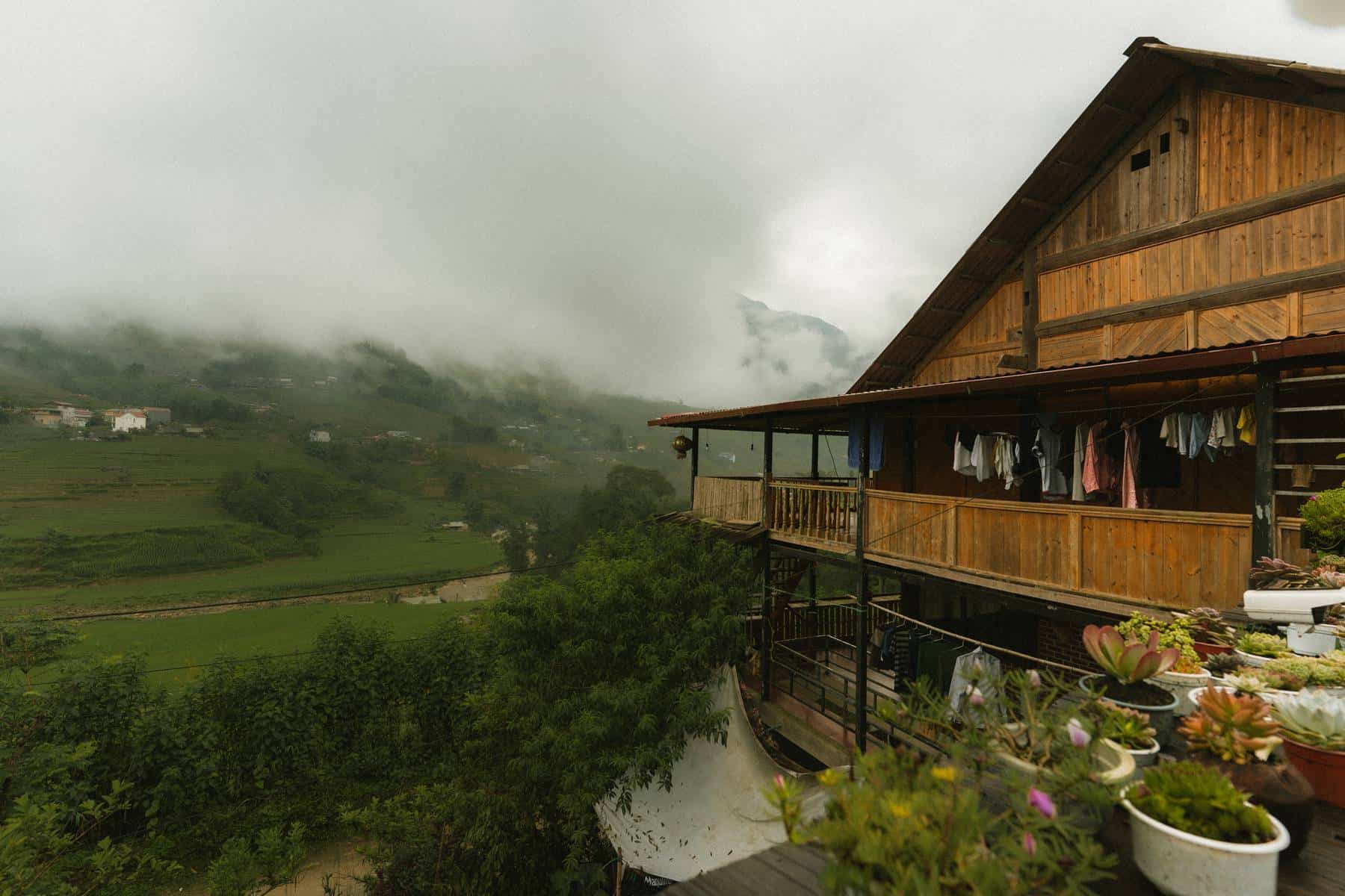 Wooden homestay balcony overlooking rice fields and misty mountains near Sapa